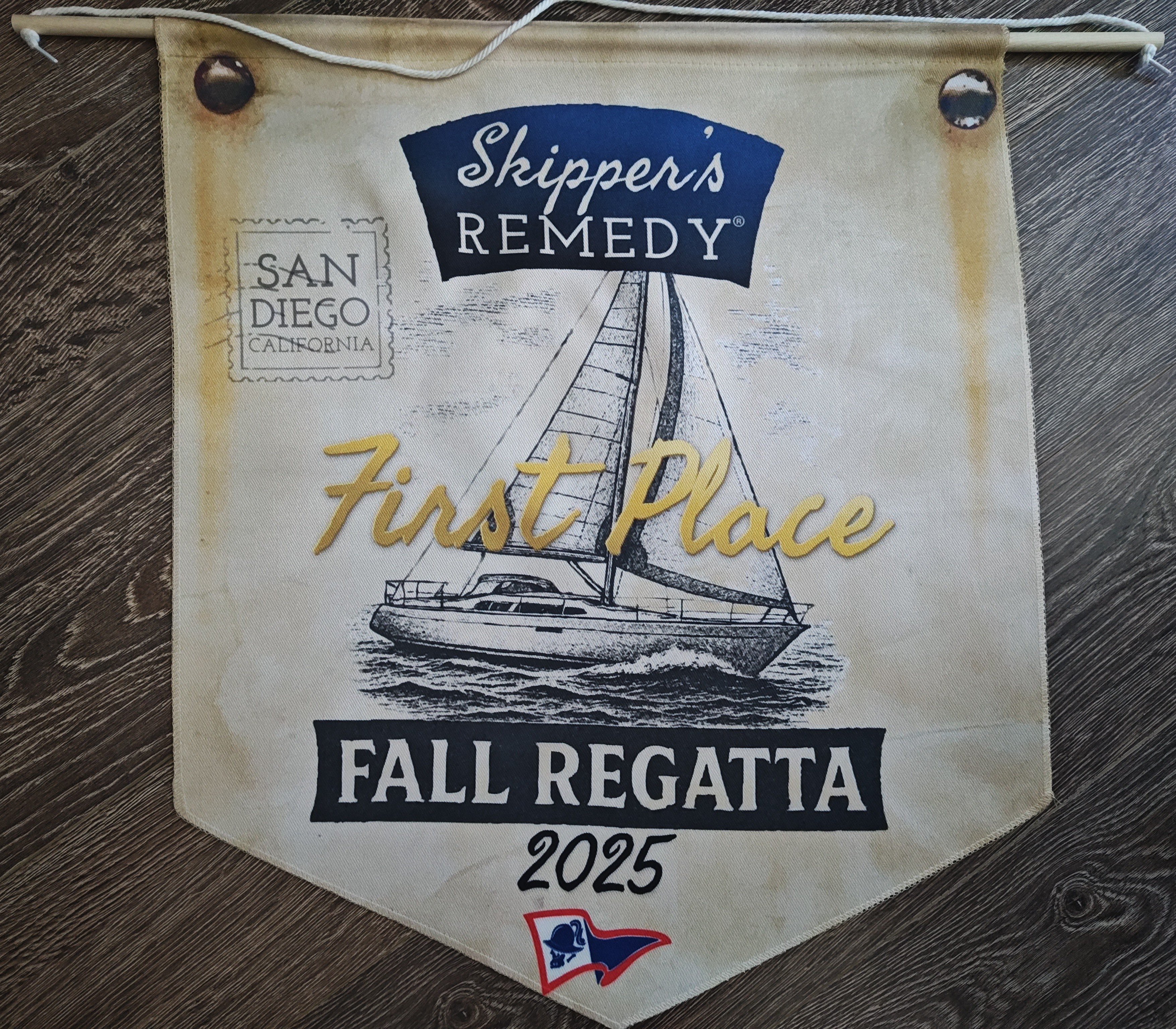 Skippers Remedy Fall Regatta banner with sailboat illustration on a wooden surface