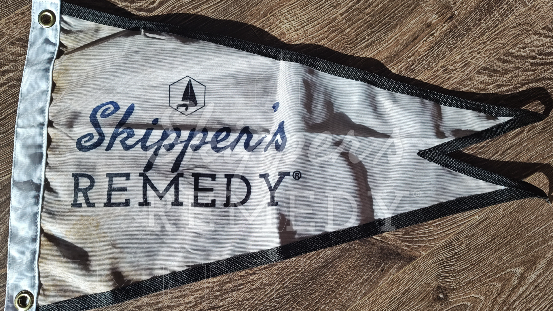 Skipper's Remedy burgee flag on a wooden surface