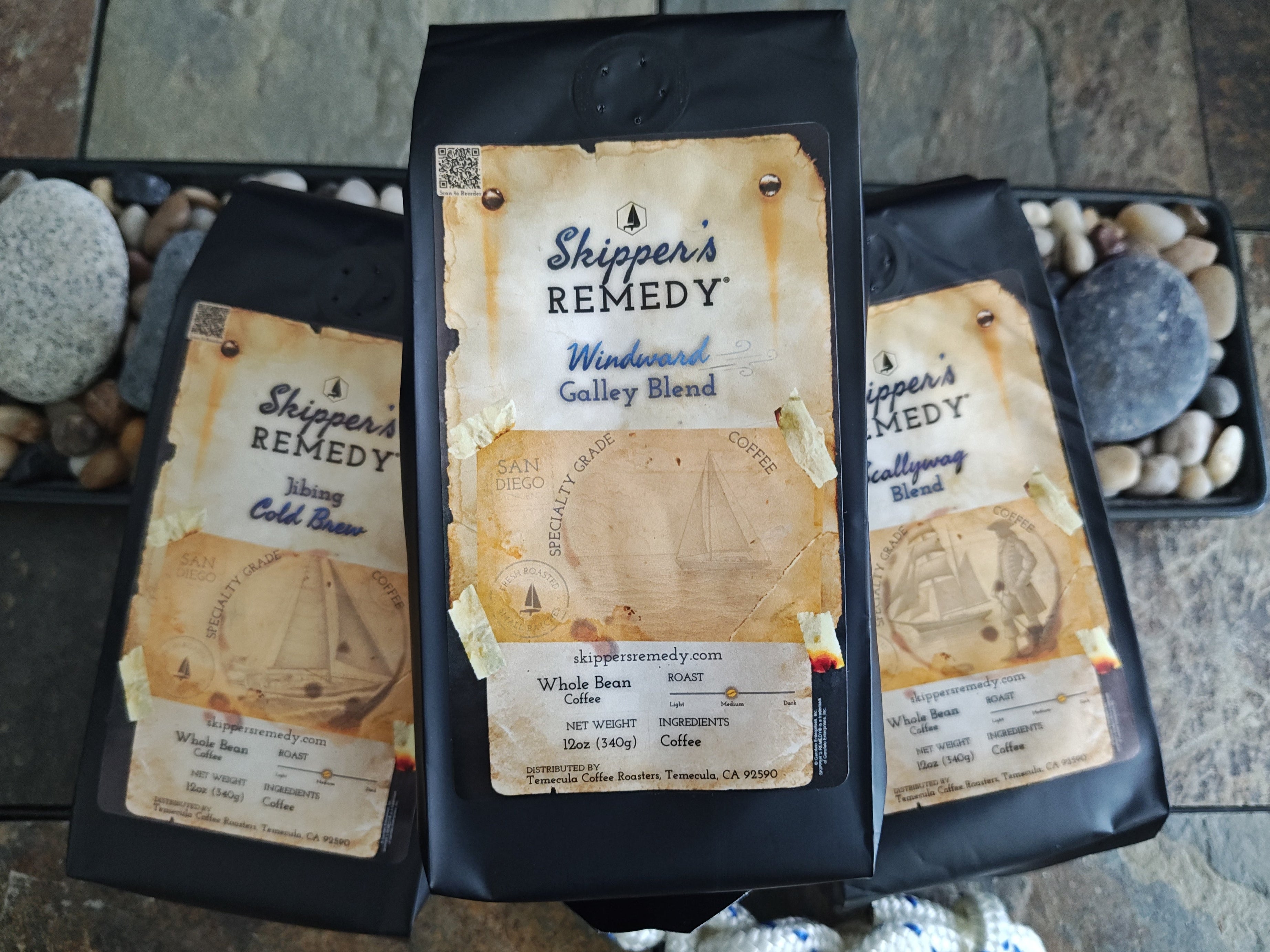 Three packages of 'Shipper's Remedy' coffee on a stone surface.