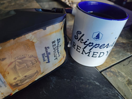 Bag of Scallywag Blend coffee next to a Skipper's Remedy coffee mug, on a stone background