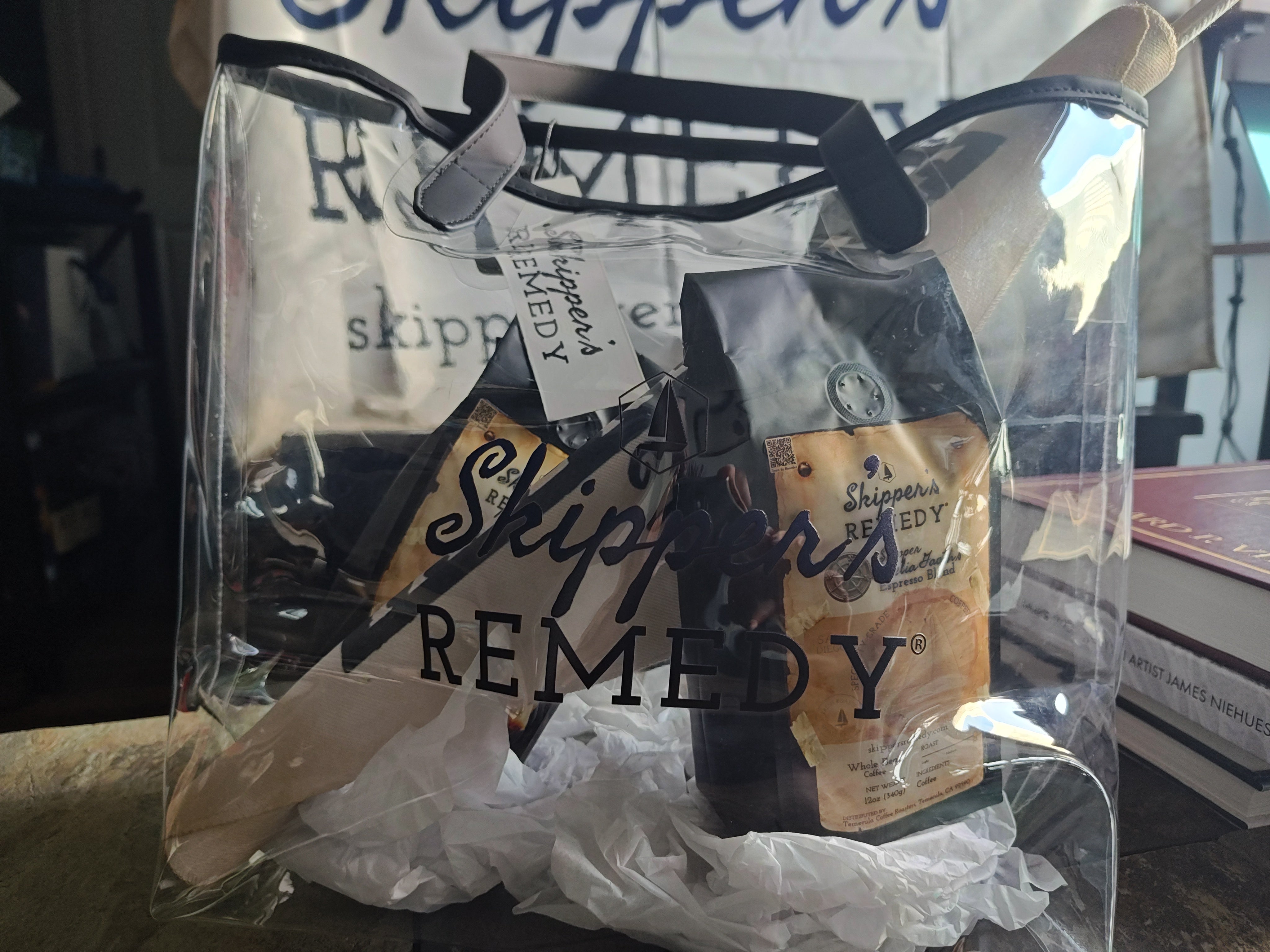 Clear plastic bag with 'Skipper's Remedy' logo, with two 12oz bags of coffee sitting on tissue papper