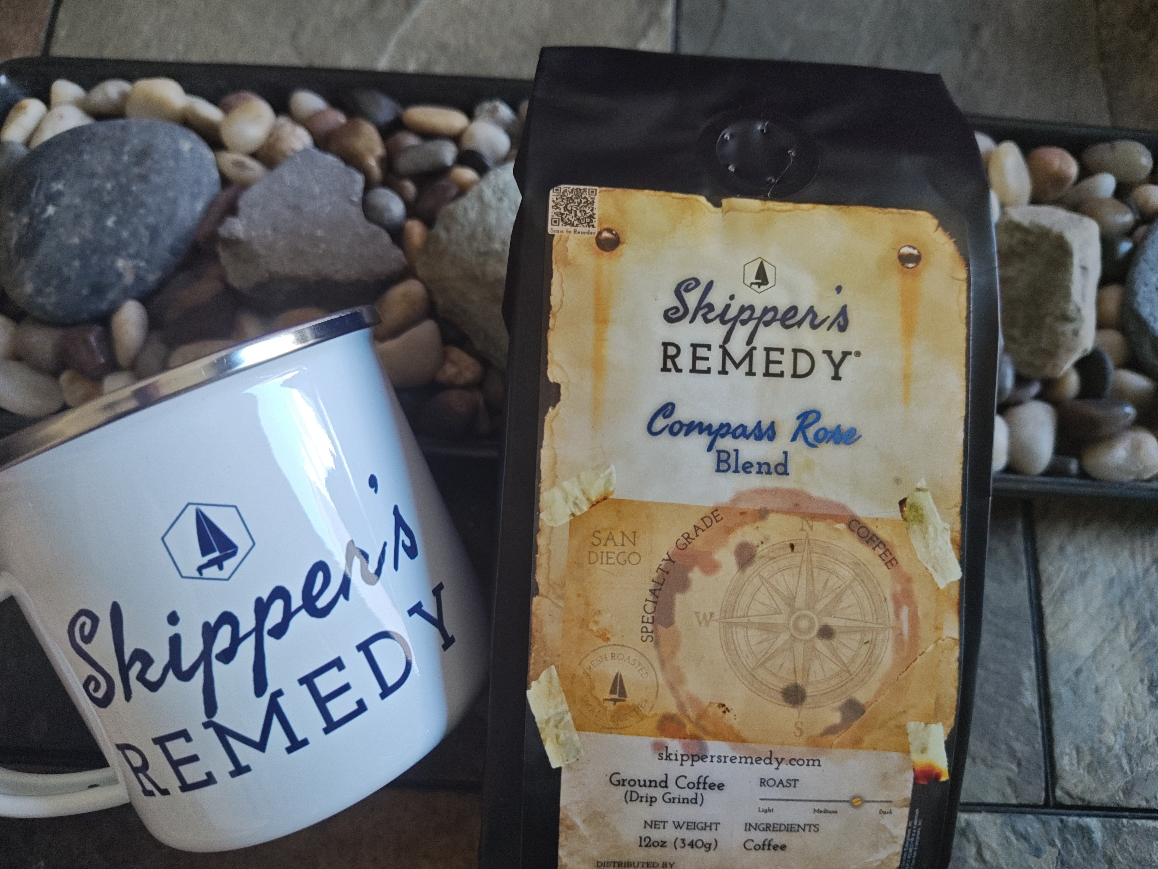 Compass Rose Blend coffee bag, from Skippers Remedy, and mug on a stone surface