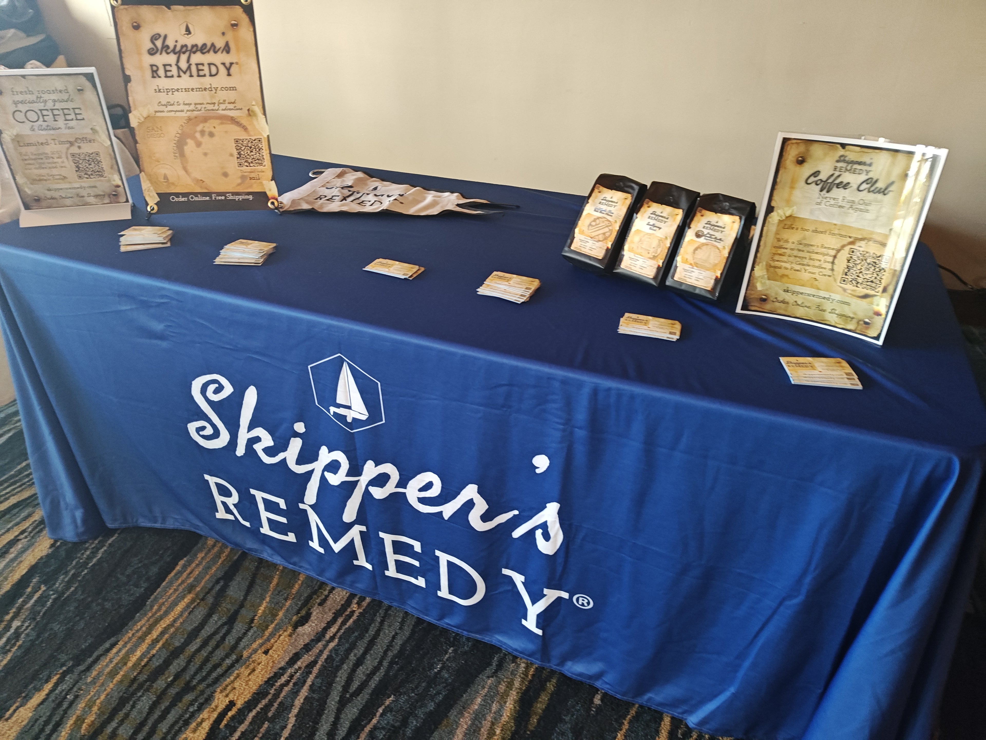 Table with Skipper's Remedy branding and products on a blue tablecloth.